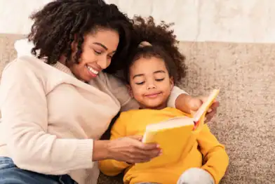 A mother and her daughter sharing a joyful reading moment, making books fun and engaging.