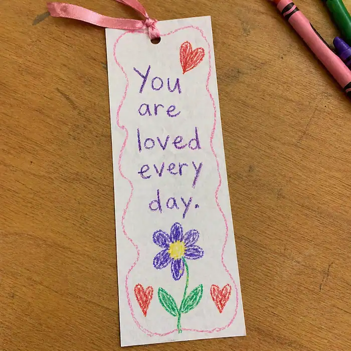 handmade bookmark with childlike writing saying you are loved every day and ribbon