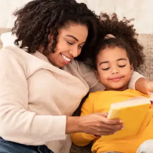 Mother and daughter reading a book together, smiling and enjoying storytime.