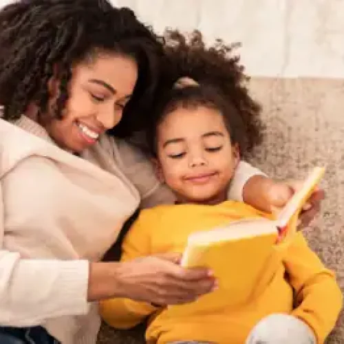 A mother and her daughter sharing a joyful reading moment, making books fun and engaging.