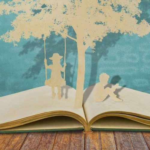 picture of a cut out book with swing and a woman sitting on swing. A male is sitting at the base of the tree.